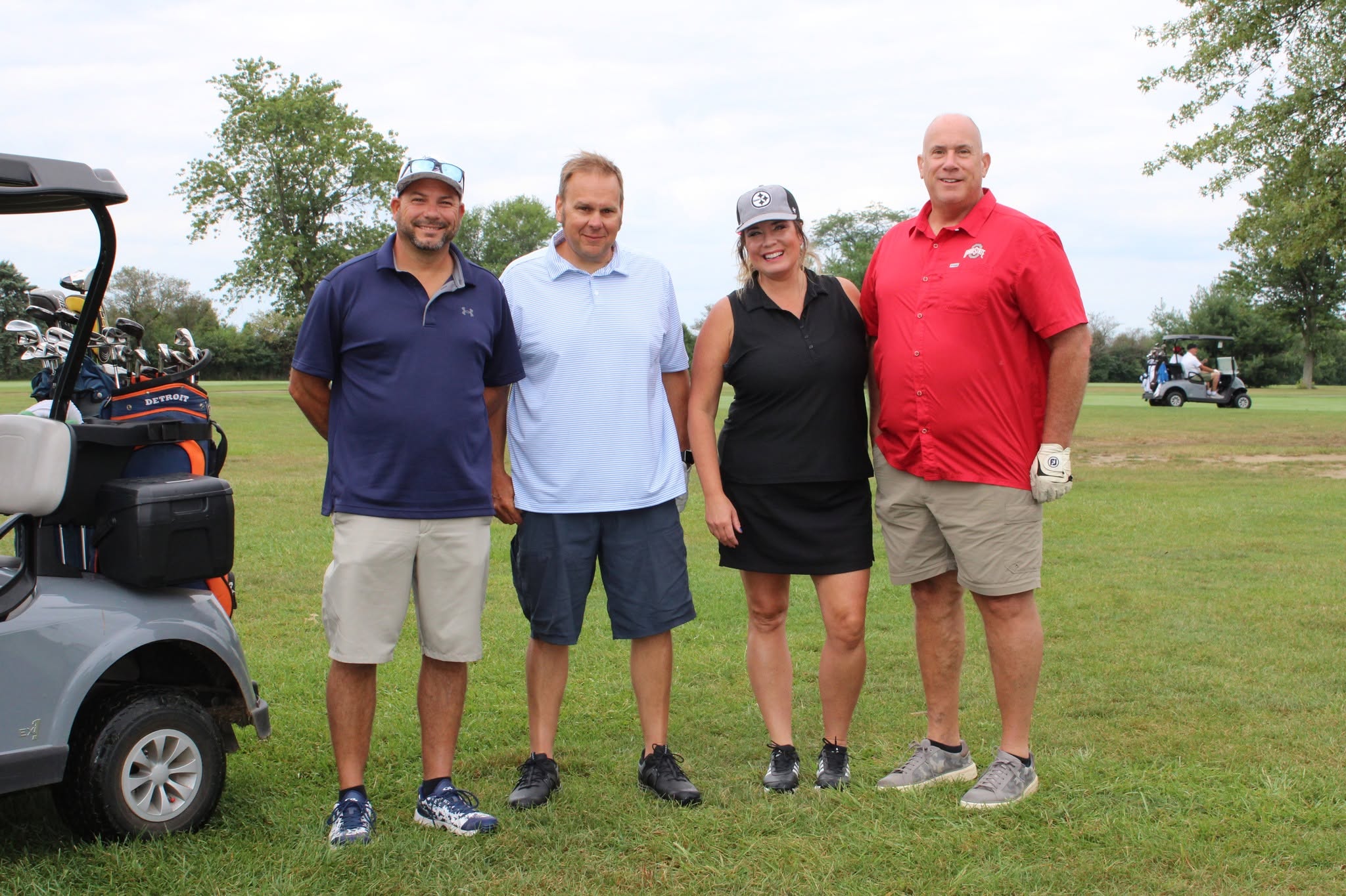 McCarthy posing by a golf cart at the Merle Trumbull Golf Outing
